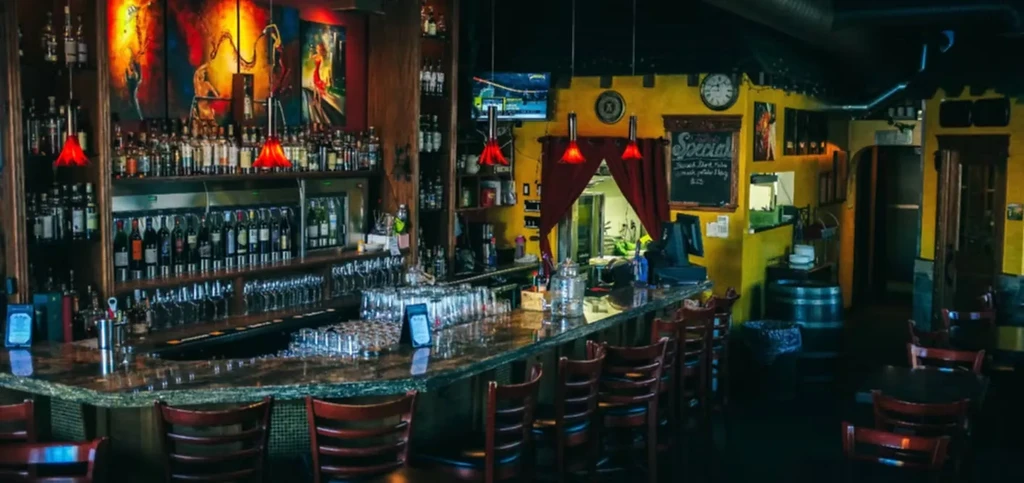 Well-stocked bar with bottles, glasses, and warm lighting in a restaurant.