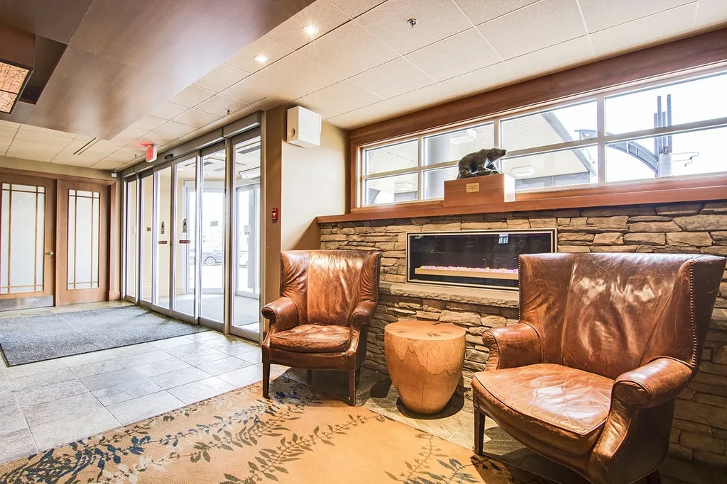 Two distressed leather armchairs, cylindrical table, stone fireplace, bear statue.