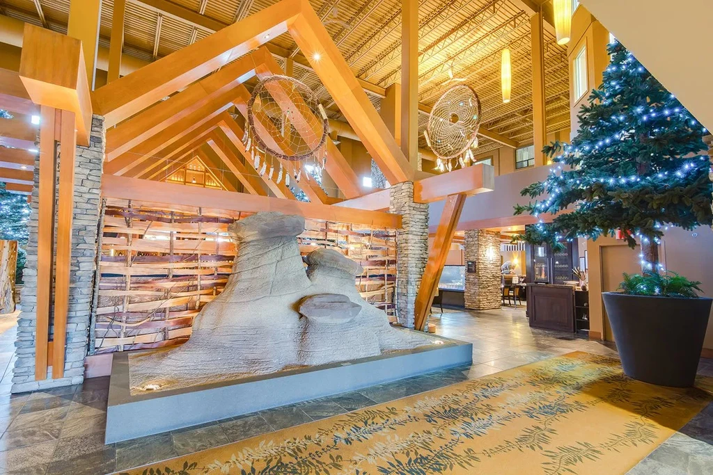 Grand lodge lobby with vaulted wood ceiling, stone pillars, rock feature.