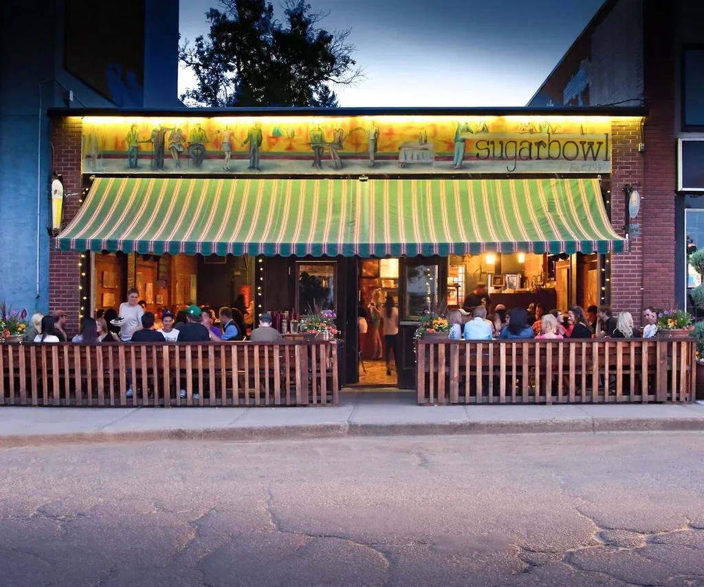 Exterior of Sugarbowl restaurant at dusk with busy patio.