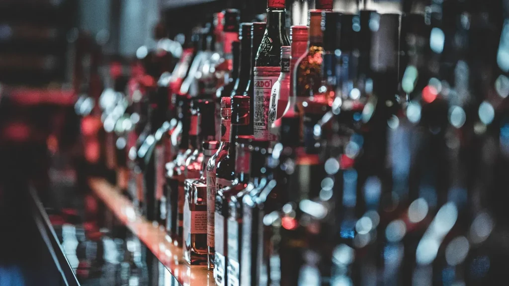 Dimly lit bar with a long row of various liquor bottles.