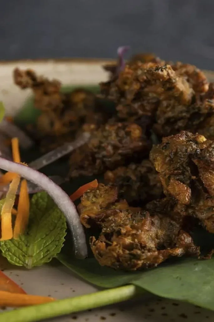 Close-up of crispy golden-brown fritters with onion, carrots, and mint.