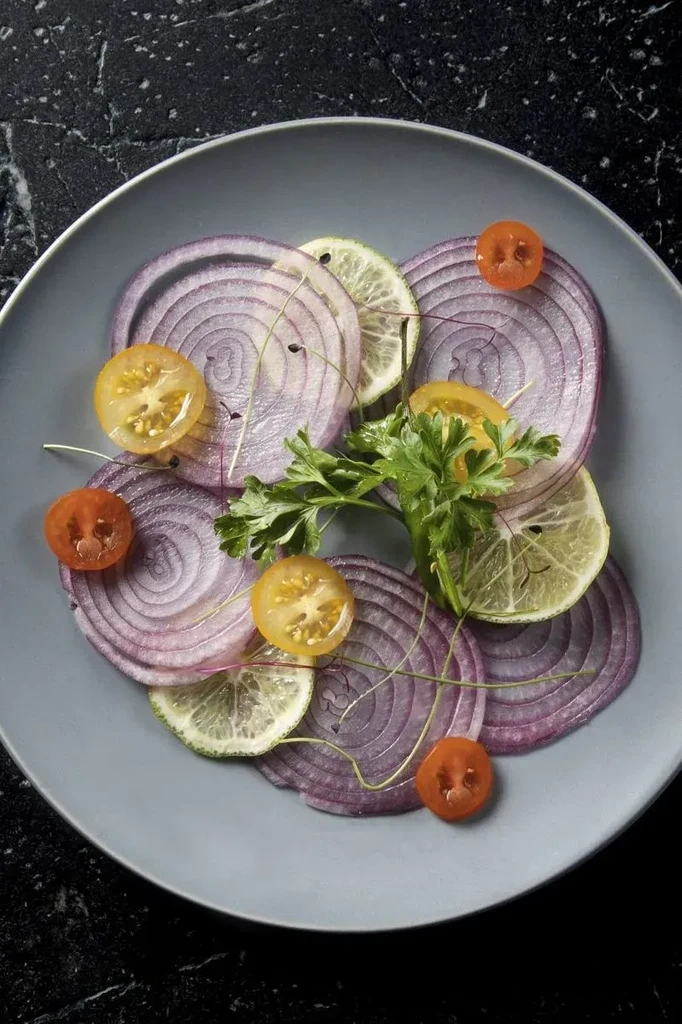 Overhead: Artfully arranged red onion, lime, tomatoes, and fresh herbs.