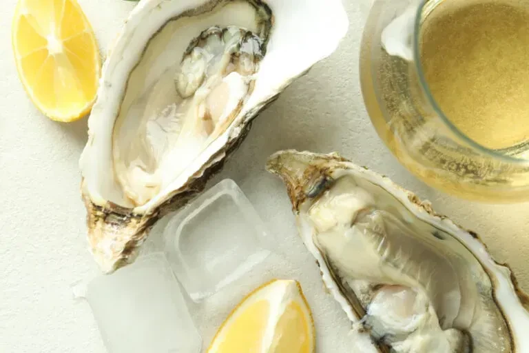 Two freshly shucked oysters with ice, lemon wedges, and sparkling wine.
