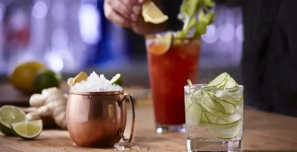 A Moscow Mule, red cocktail, and cucumber drink on a rustic wooden bar.