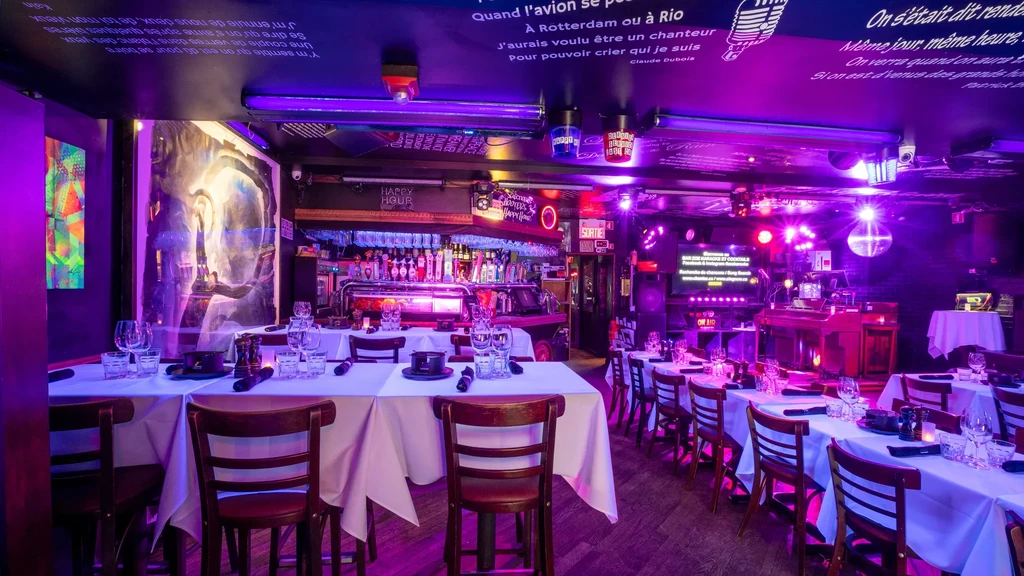 Purple-lit, empty restaurant and bar with set tables and karaoke.