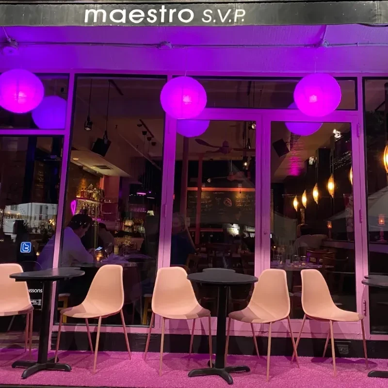 Maestro S.V.P. bar exterior glowing purple at night with outdoor seating.
