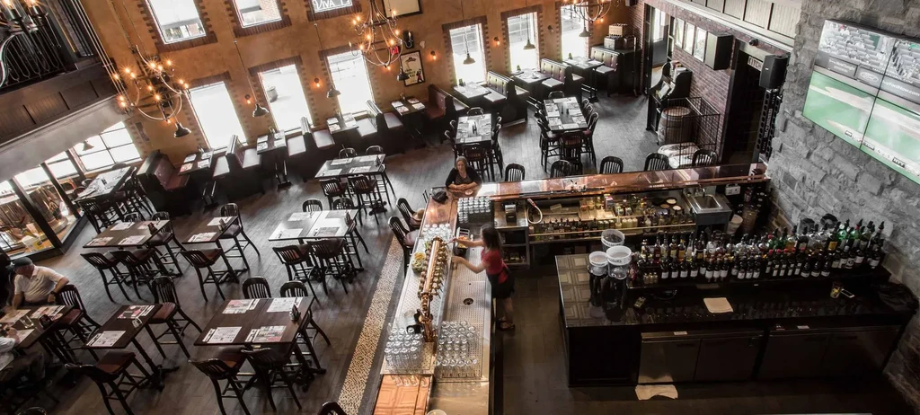 Spacious, warm, modern industrial restaurant bar with brick walls.