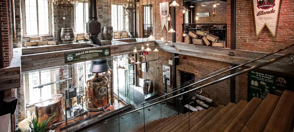 Multi-level brewpub interior with exposed brick and a copper kettle.