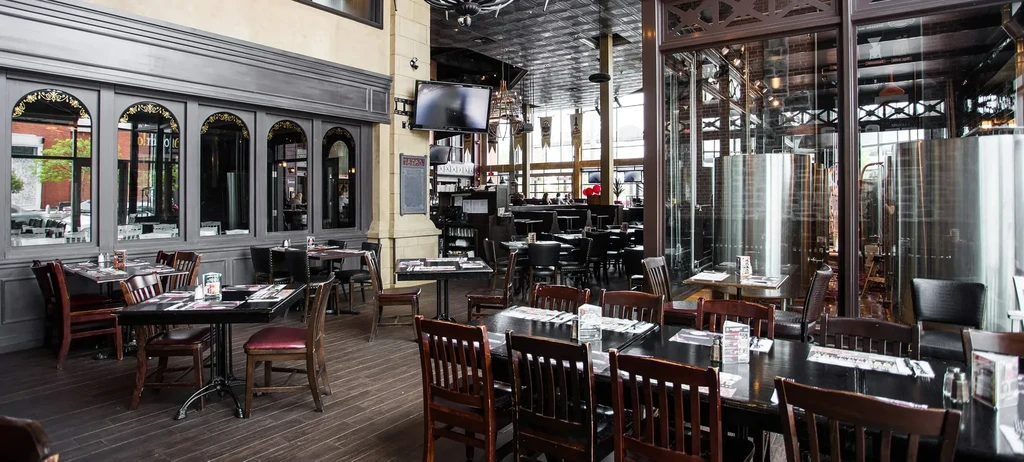 Spacious brewpub interior with dining areas, bar, and gleaming brewing tanks.