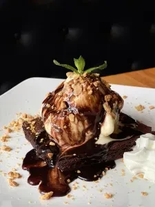 Brownie with melting ice cream, chocolate syrup, nuts, mint, whipped cream.