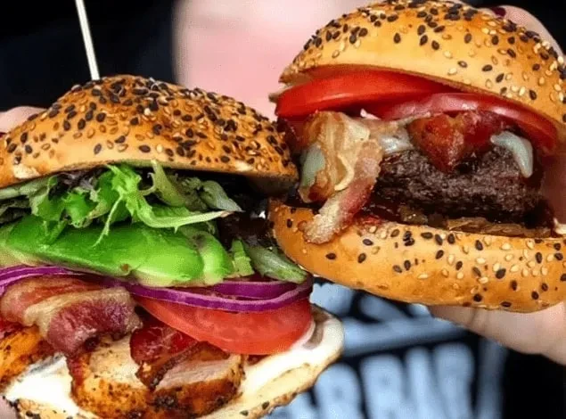 Close-up of two layered burgers: chicken with avocado, beef with cheese.