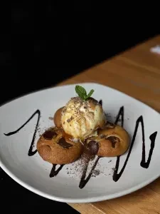 Close-up of three baked items, vanilla ice cream, mint, and chocolate sauce.