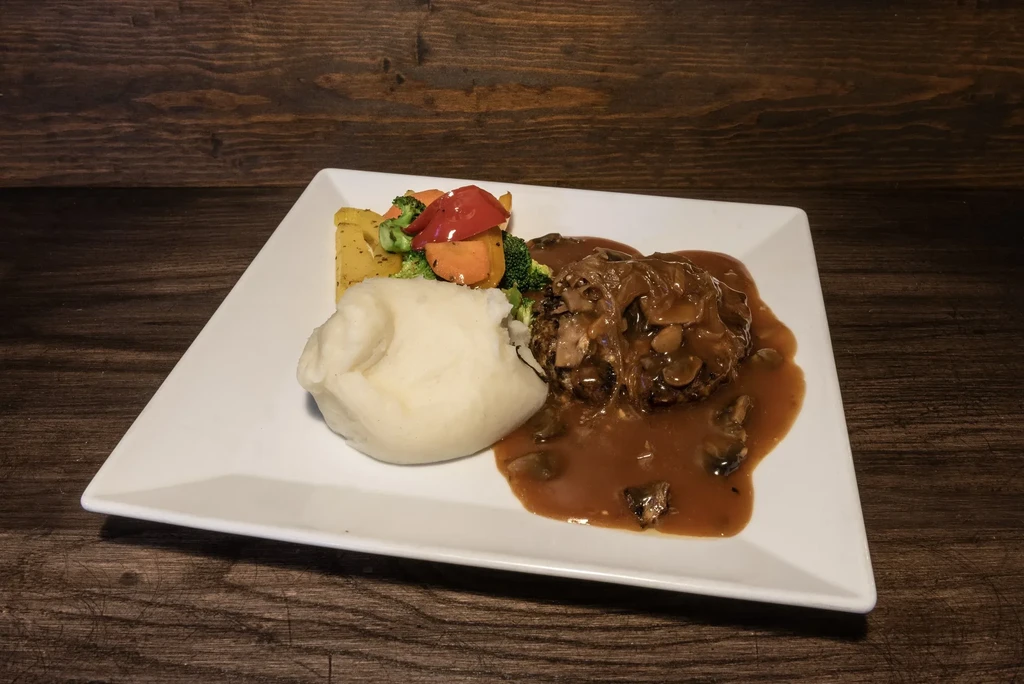 Mashed potatoes, colorful vegetables, and mushroom gravy over protein.