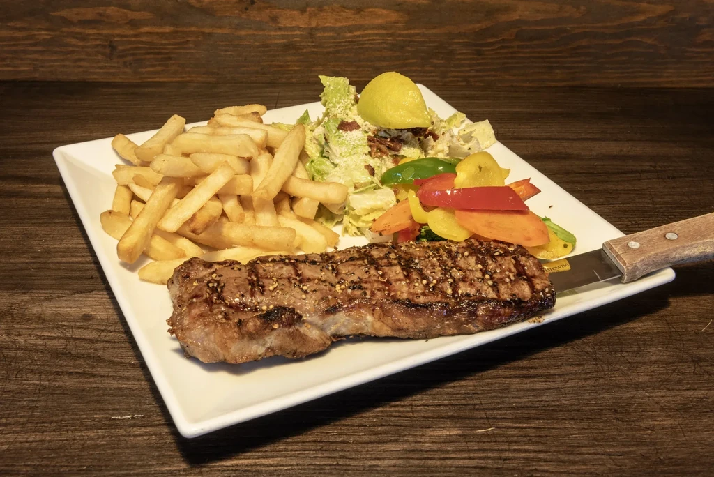 Grilled steak, golden fries, green salad, and colorful sautéed vegetables.