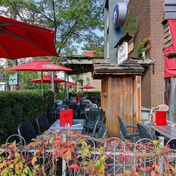 Empty restaurant patio with red umbrellas and colorful autumn foliage.