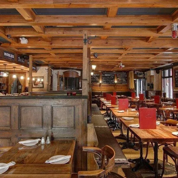 Rustic restaurant dining area with wooden beams, set tables, and menu chalkboards.