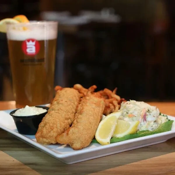 Golden fried fish and chips with coleslaw, dipping sauce, and beer.