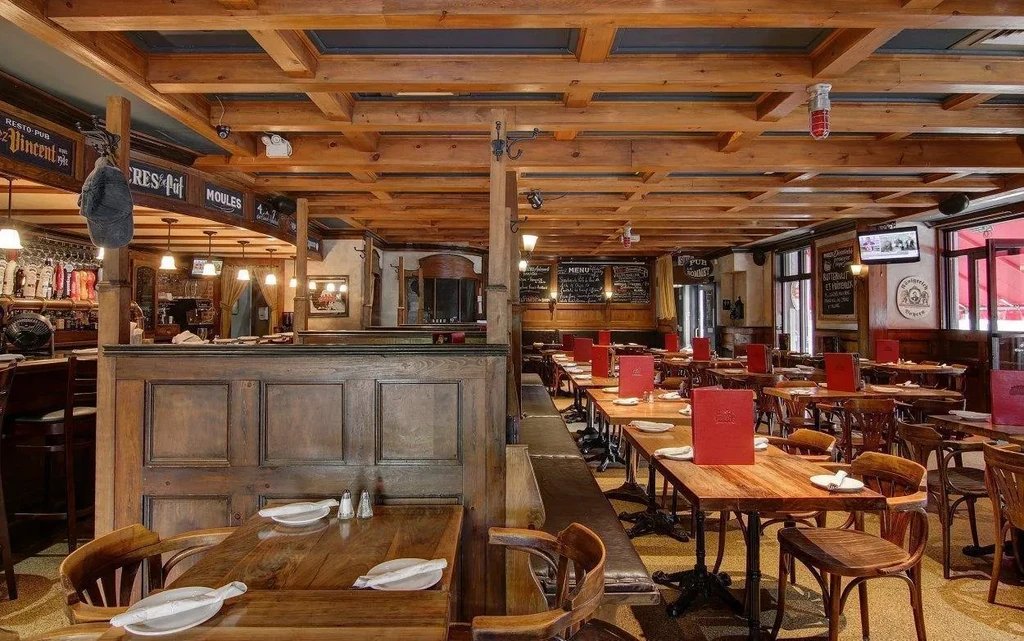 Rustic European pub interior with wooden decor, bar, and menu chalkboards.