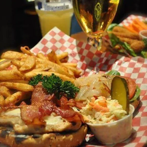 Bacon burger, thick-cut fries, coleslaw, and drinks in a diner.