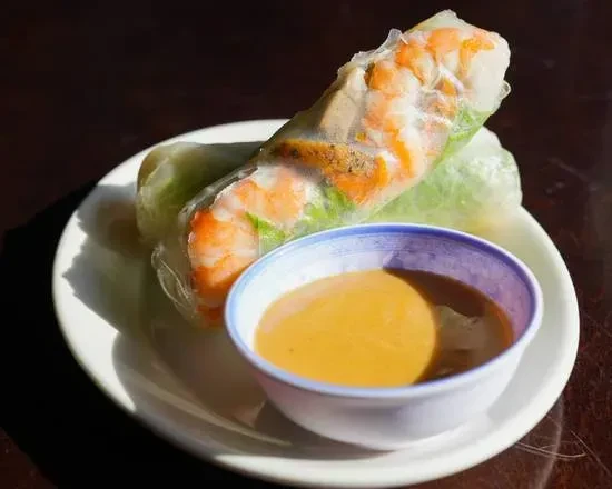 Two translucent spring rolls showing shrimp, lettuce, and peanut sauce.