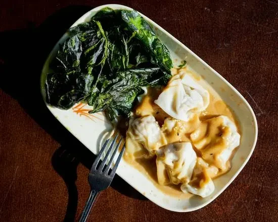 Plate of creamy dumplings, leafy greens, and a silver fork.