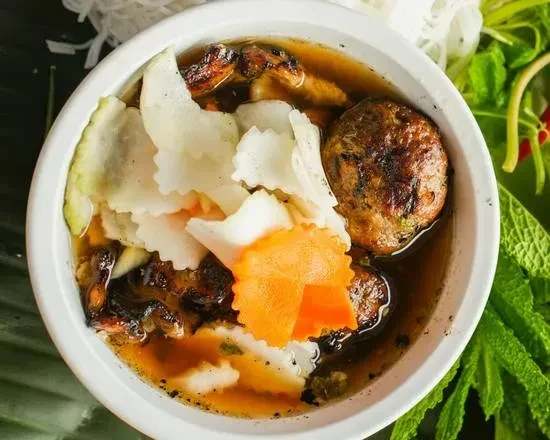 White bowl of Bún chả with grilled meat, pickled vegetables, and broth.