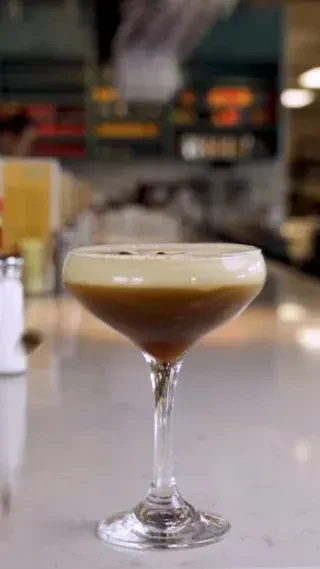 Espresso Martini in a martini glass with foam and coffee bean garnish.