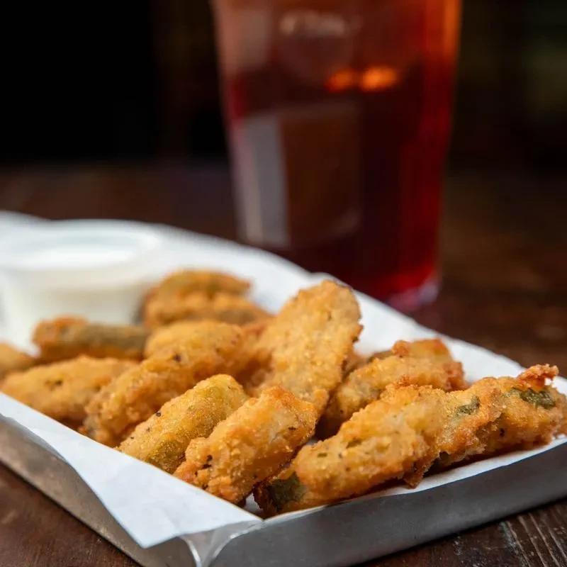 Close-up of crispy fried food and white dipping sauce in a tray.