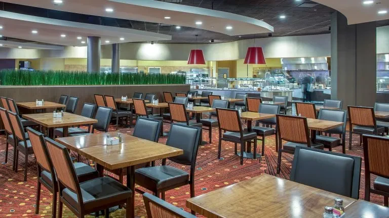 Well-lit restaurant dining area with tables, chairs, and a buffet line.