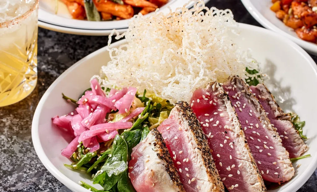 Seared ahi tuna with sesame crust, pickled onions, and greens.