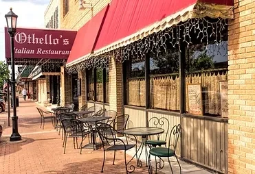 Othello's Italian Restaurant exterior: red awning, icicle lights, outdoor dining area.