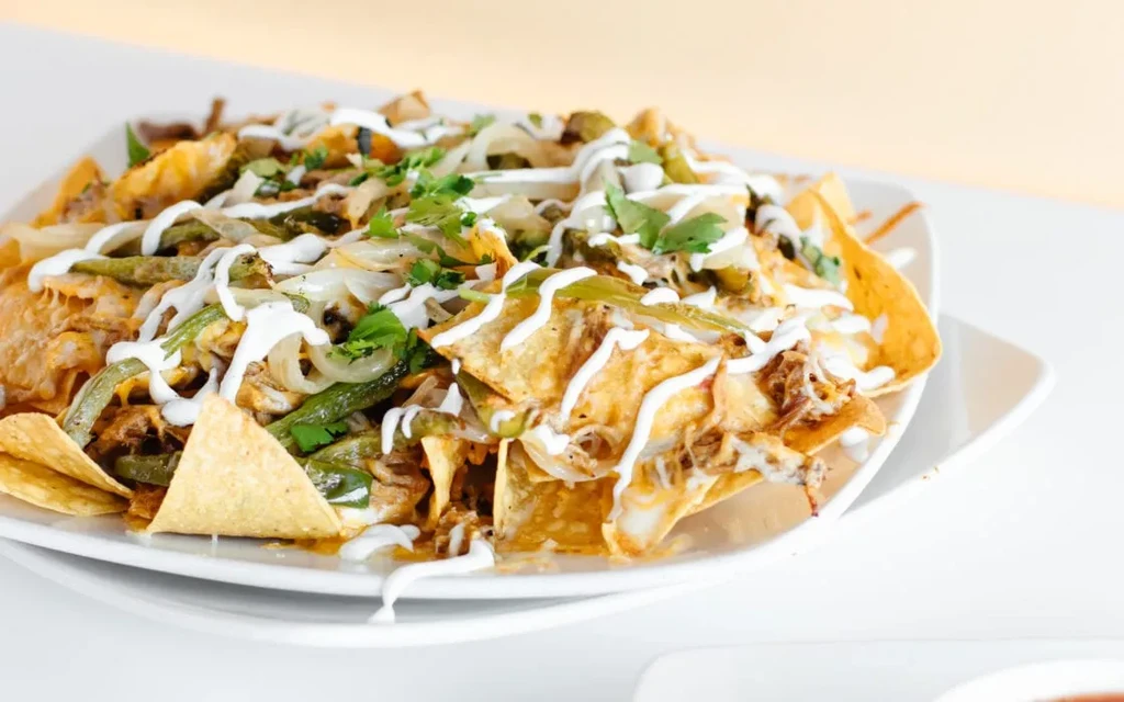 Loaded nachos with meat, cheese, peppers, sour cream, and cilantro.