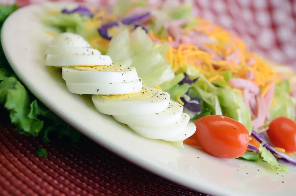 Colorful chef's salad with eggs, lettuce, cheese, and meat.