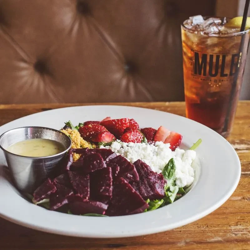 Colorful beet, strawberry, cheese salad and iced tea on table.