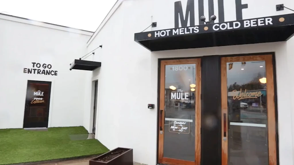 The Mule restaurant exterior: white walls, black accents, 'Hot Melts' advertised.