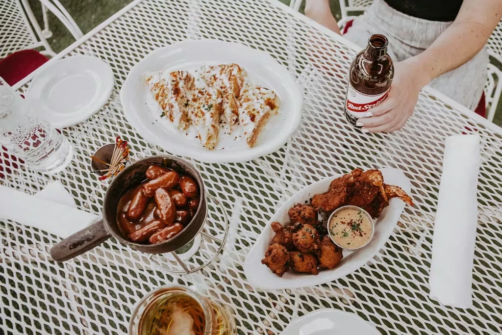 Table with quesadillas, sausages, fried wings, and Red Stripe beer.