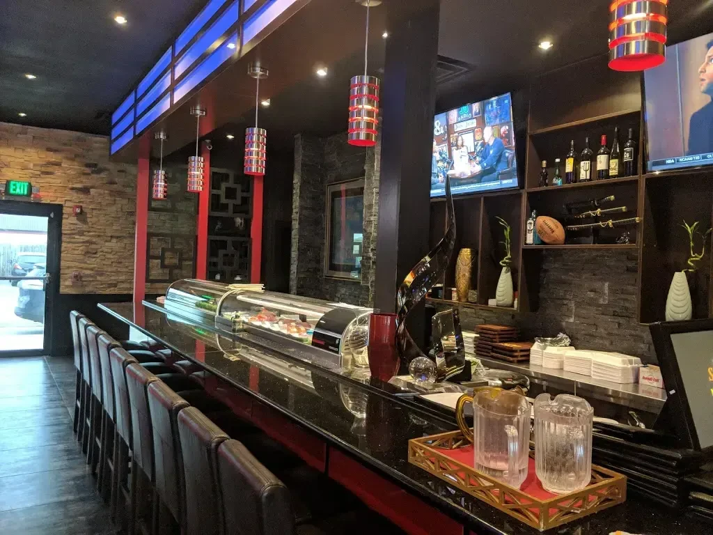 Modern Asian-inspired restaurant interior with sushi bar and TVs.