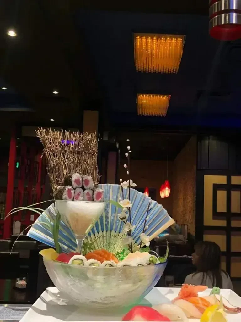 Lavish sushi platter with fan, flowers, tuna maki in upscale restaurant.