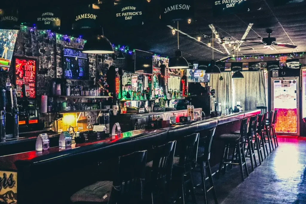 Colorful neon lights illuminate a vibrant, empty bar interior.