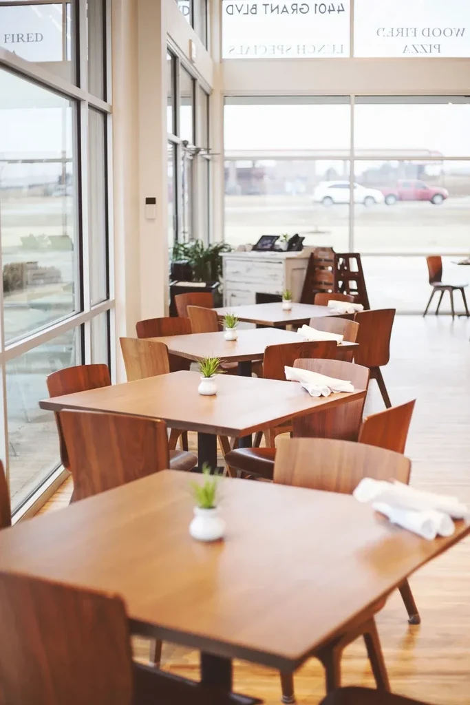 Empty modern cafe dining area with wooden tables and large windows.