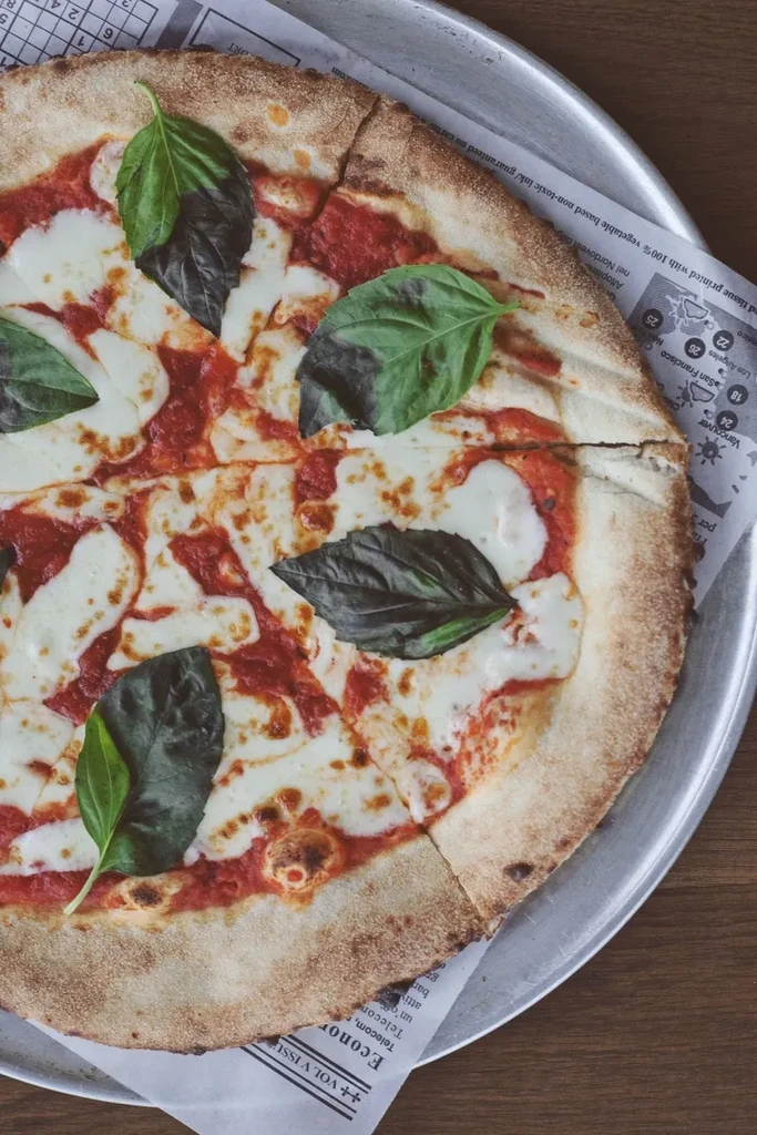 Sliced Margherita pizza with red sauce, mozzarella, and fresh basil.