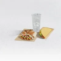 Minimalist studio shot of a burrito, triangular food, and an iced drink.