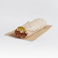 Single burrito revealing meat, cheese, and herbs on brown paper.