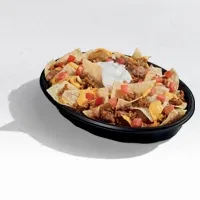 Close-up of nachos with meat, cheese, tomatoes, and sour cream.