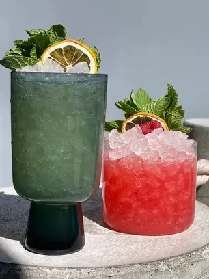 Green and red iced drinks with mint and citrus garnishes.