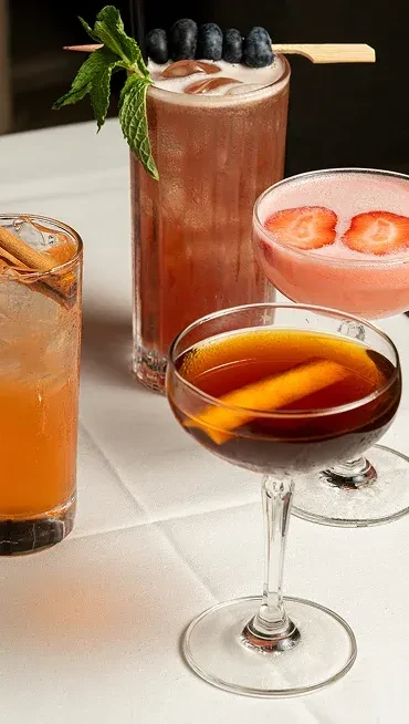 Four cocktails: orange with cinnamon, berry, strawberry, and orange peel.