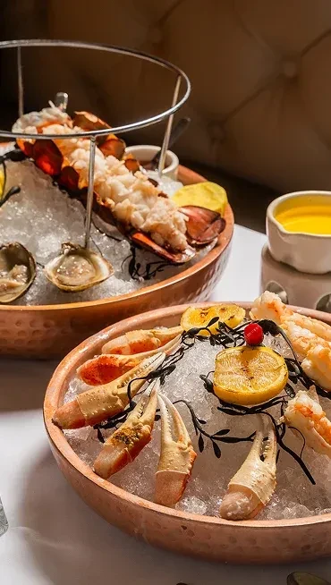 Tiered seafood platter featuring cooked lobster tail, crab claws, and oysters.
