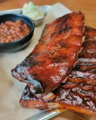 Two racks of saucy barbecued ribs, baked beans, and creamy green side.