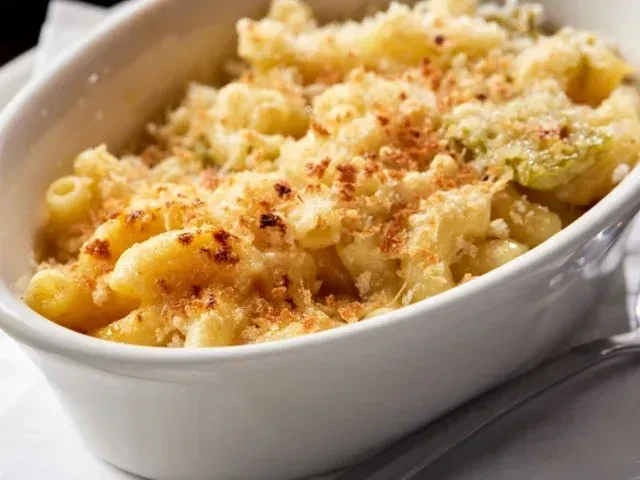 Baked macaroni and cheese topped with golden breadcrumbs and green elements.